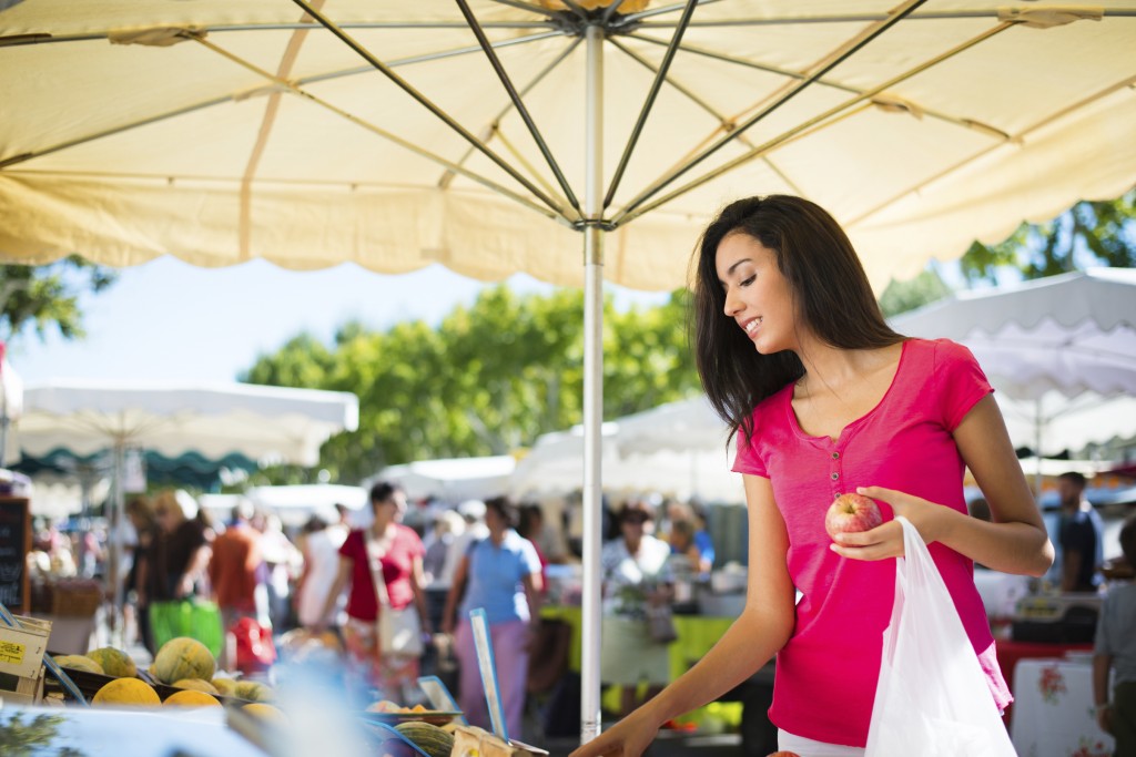 cheerful healthy young woman shopping in farmers market buying fresh organics fruits and vegetables