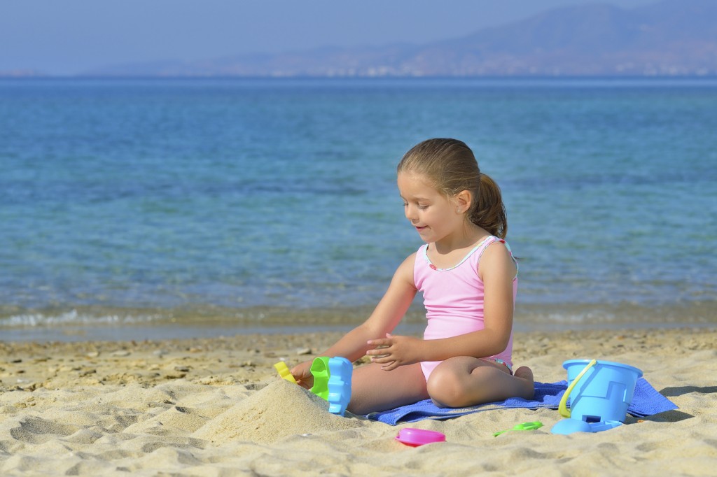 Adorable toddler girl playing with her toys at the beach